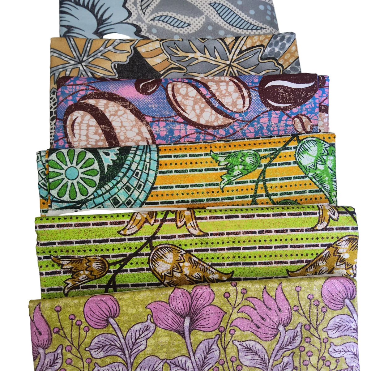 A stack of folded patterned fabrics in various colors and designs, including stripes, florals, and abstract prints, displayed on a white fabric background.