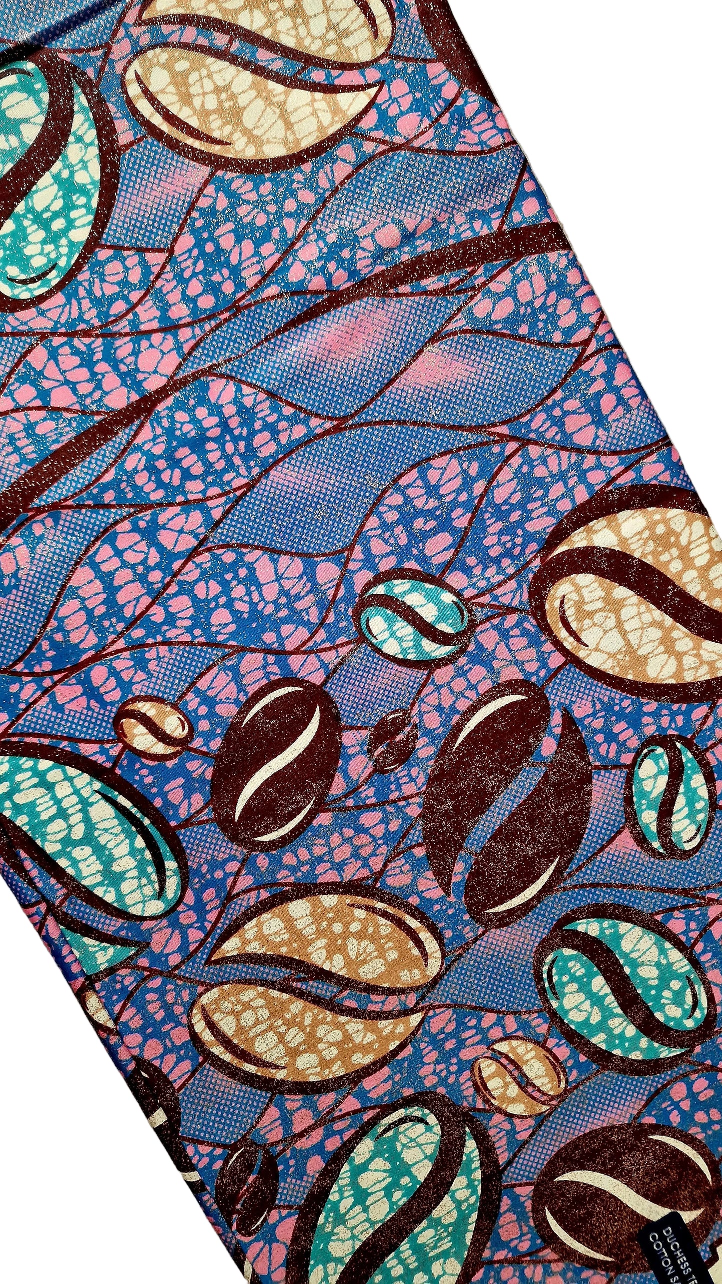 A close-up of a patterned fabric featuring coffee beans and leaf-like shapes in blue, pink, teal, brown, and beige, laid diagonally on a neutral textured surface.