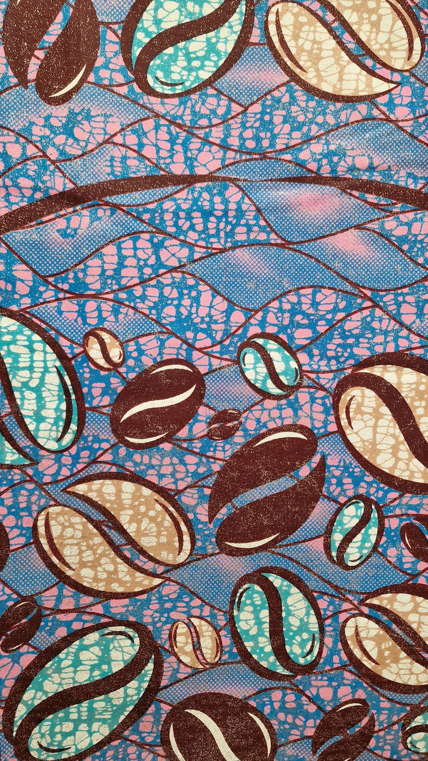 A close-up of patterned fabric with a coffee bean motif over a blue and pink textured background. The fabric has a woven texture and a small label at the bottom reading 'Duchess Tex Prime Suite' and 'Rome Wax Holland'.