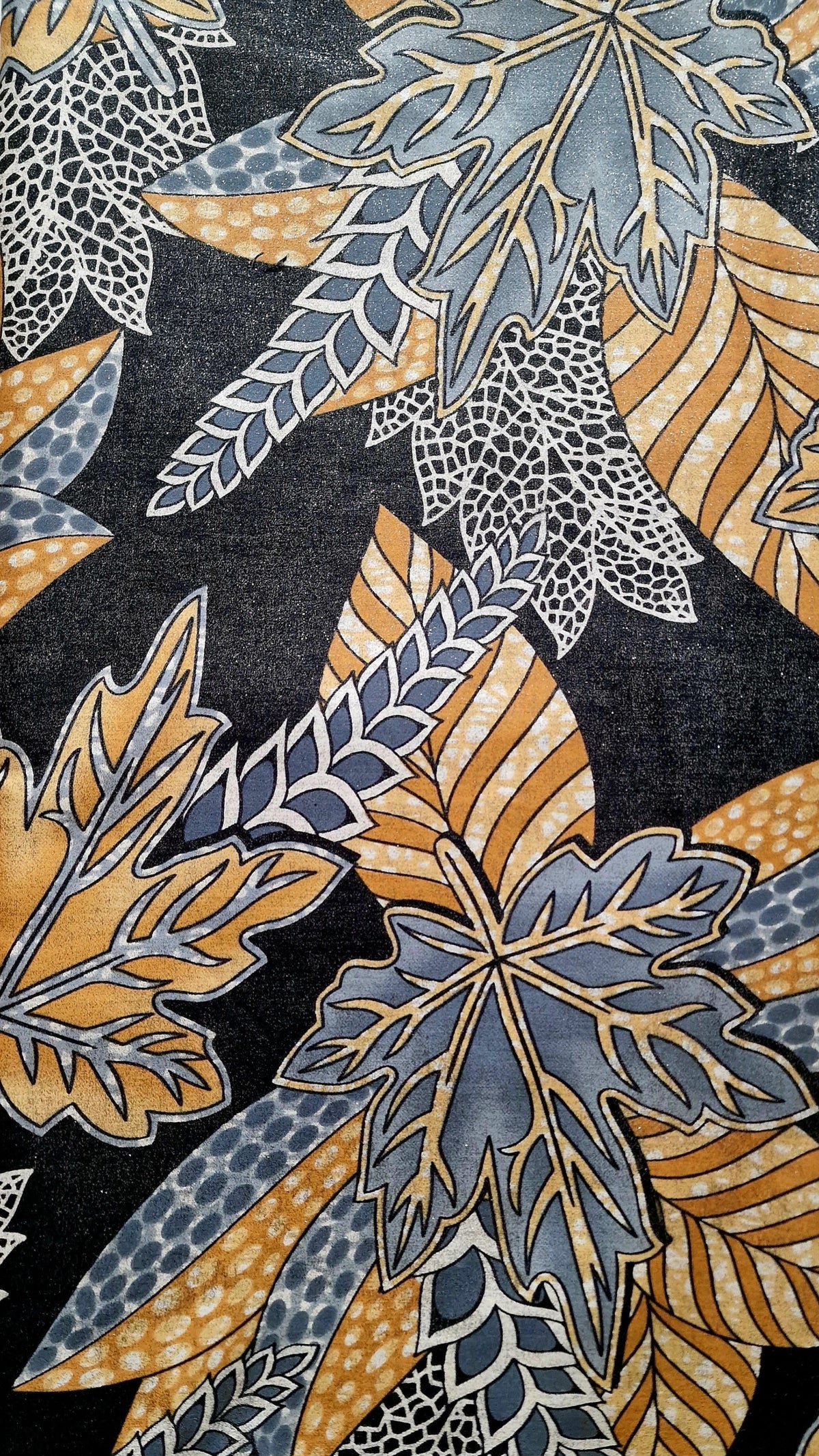 A close-up of a patterned fabric featuring stylized autumn leaves in muted blue-gray, mustard yellow, and white on a dark charcoal background.