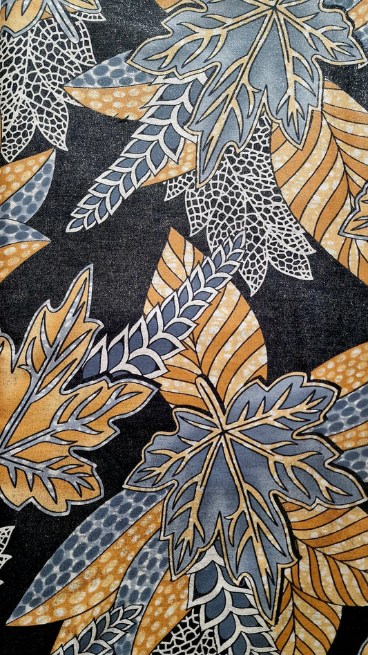 A close-up of a patterned fabric featuring stylized autumn leaves in muted blue-gray, mustard yellow, and white on a dark charcoal background.