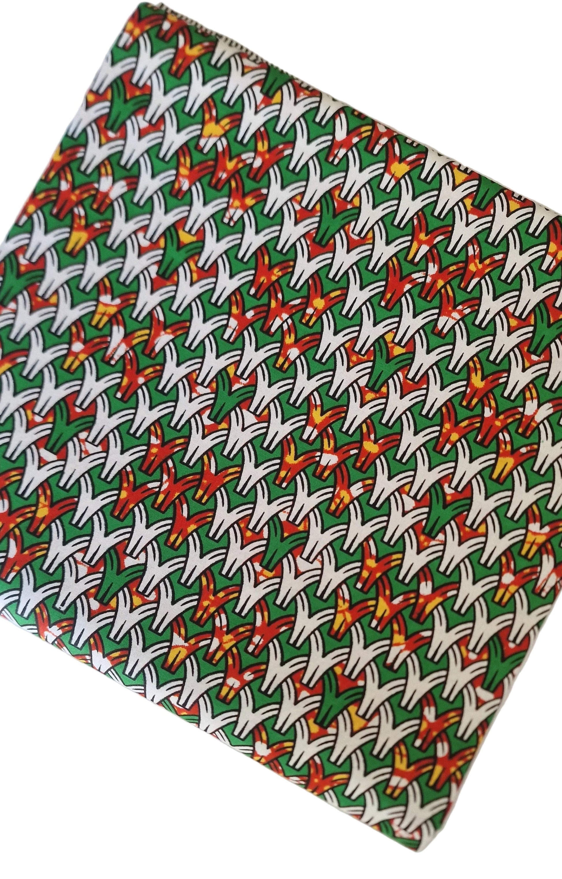 100% cotton African wax fabric featuring a vibrant green background with a repeating geometric pattern of white curved shapes and red, orange, and yellow starburst accents.