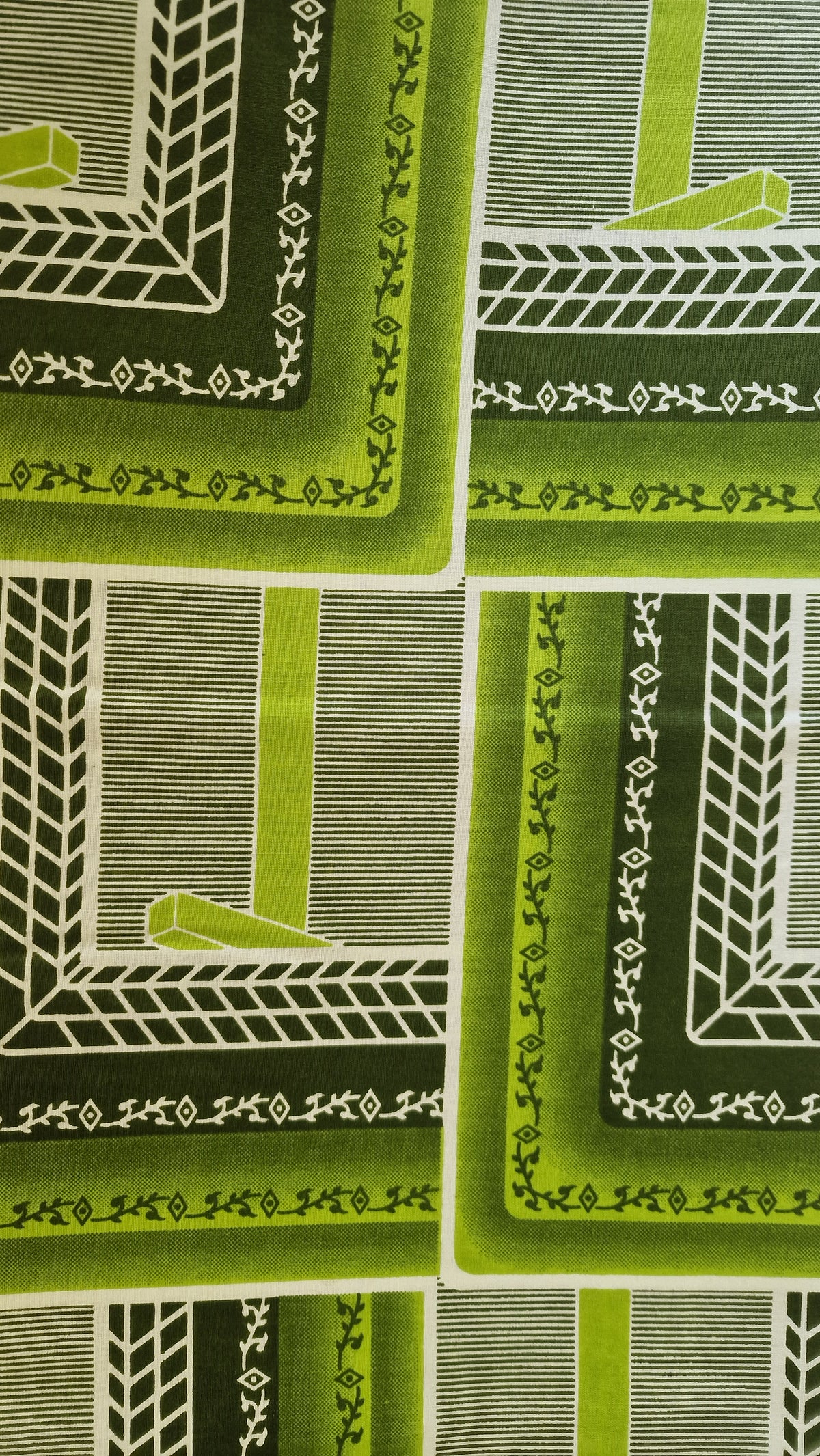 African Wax print featuring a retro geometric pattern in shades of green, olive, and white. The pattern consists of nested rectangular frames with striped and textured details