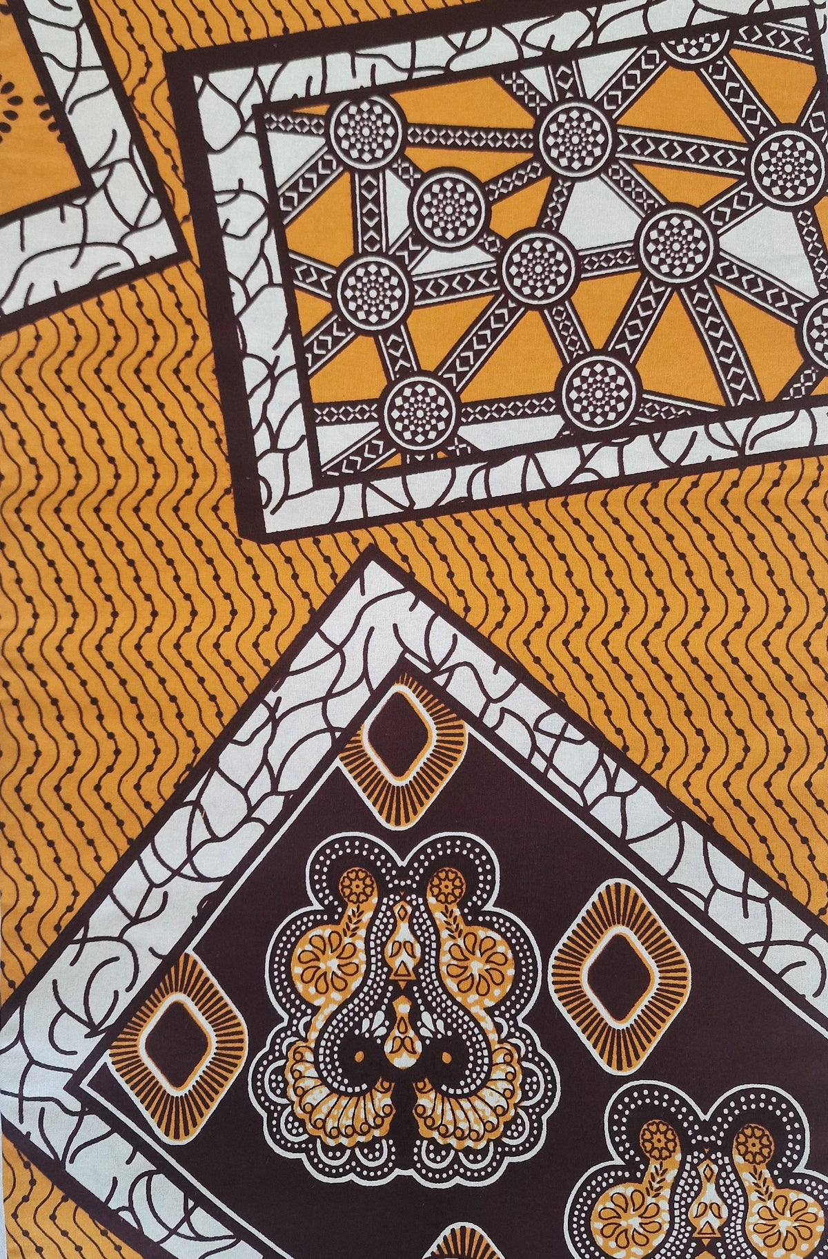 Patterned Ankara print featuring bold geometric and ornamental motifs in mustard yellow, white and dark brown