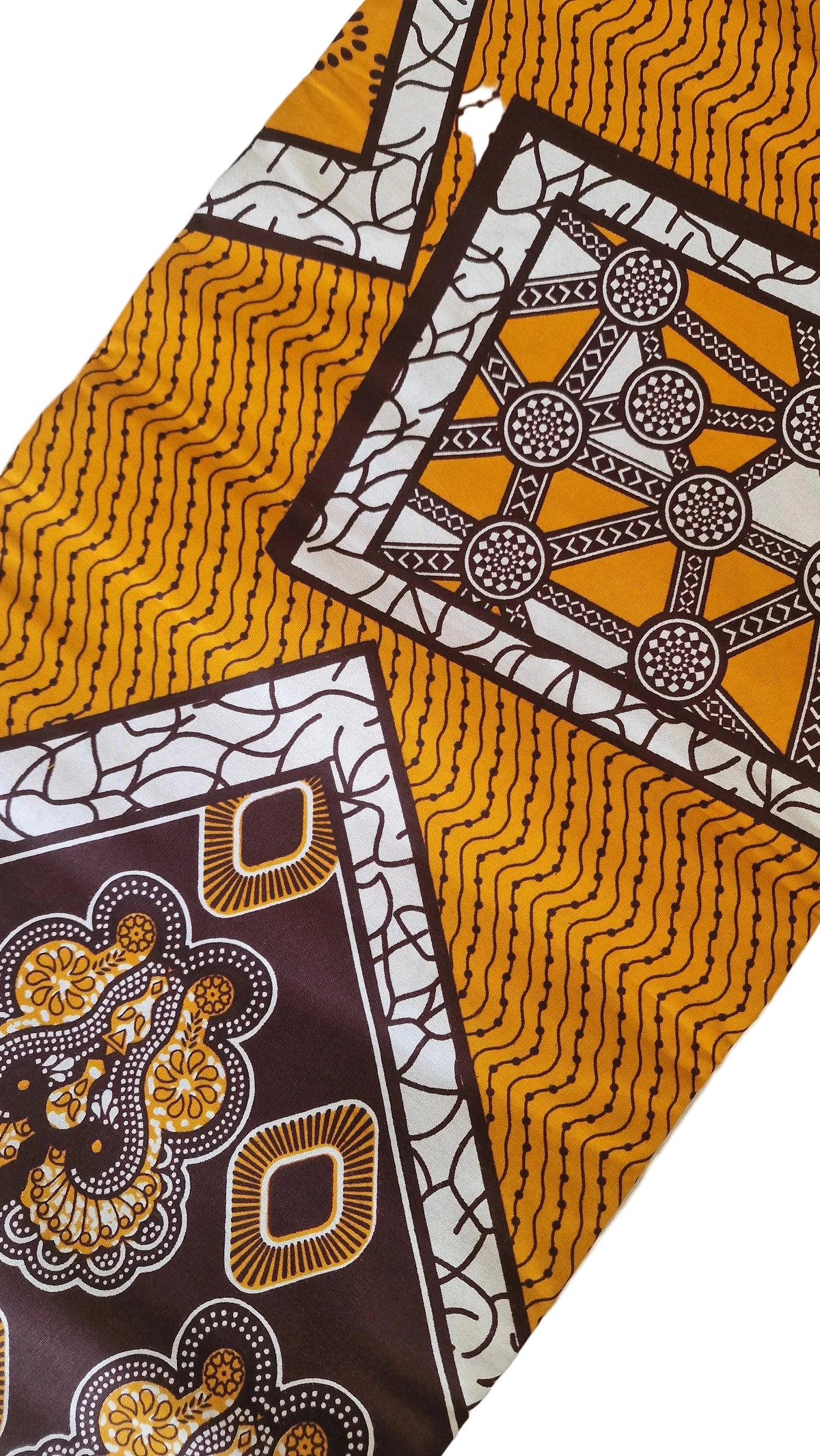 Patterned Ankara print featuring bold geometric and ornamental motifs in mustard yellow, white, dark brown, and black.