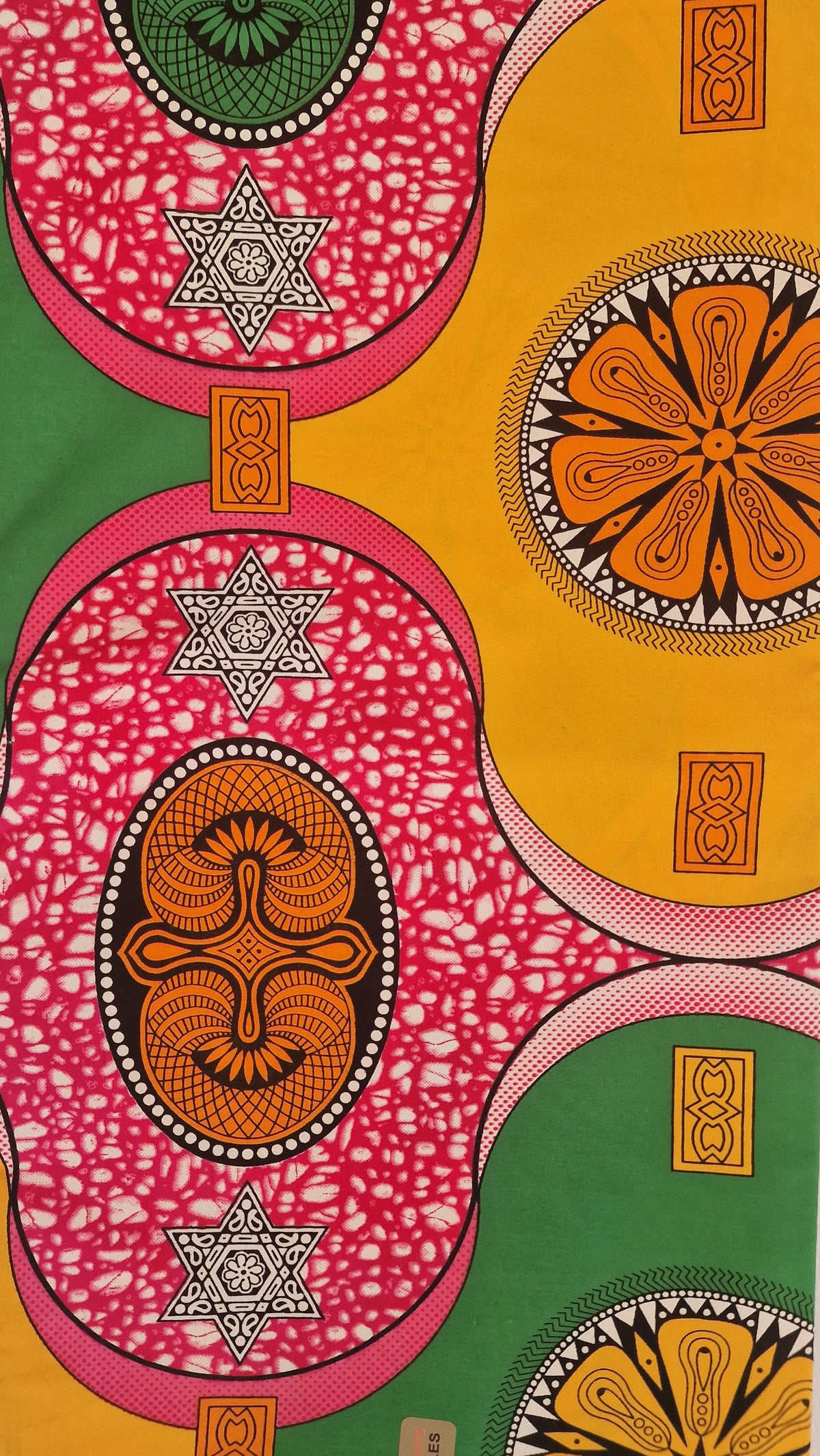 Bold African wax print pattern, featuring large overlapping circles and floral motifs in pink, yellow, green, orange, and black. 