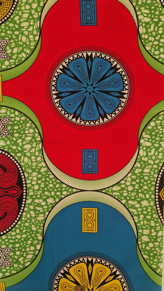 Vibrant African wax print fabric featuring a bold geometric pattern with large red, green, and blue circular shapes and intricate black and yellow details.