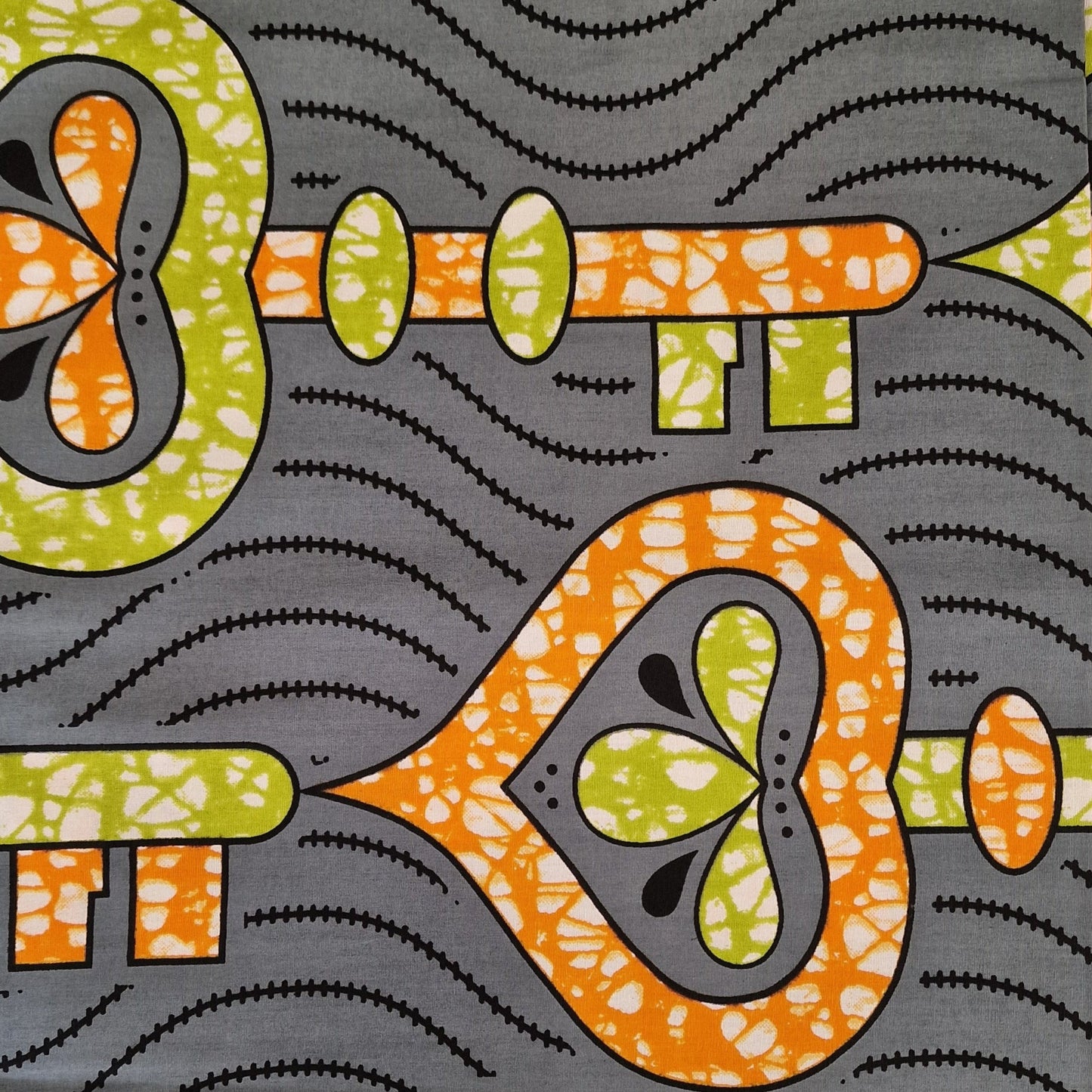 African wax print pattern featuring  orange and green mix key motifs on a gray background.